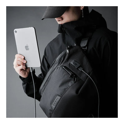 Alpaka Bravo Sling Max V2, слінг на плечі, чоловік тримає планшет, кабель заряджання виведений через порт